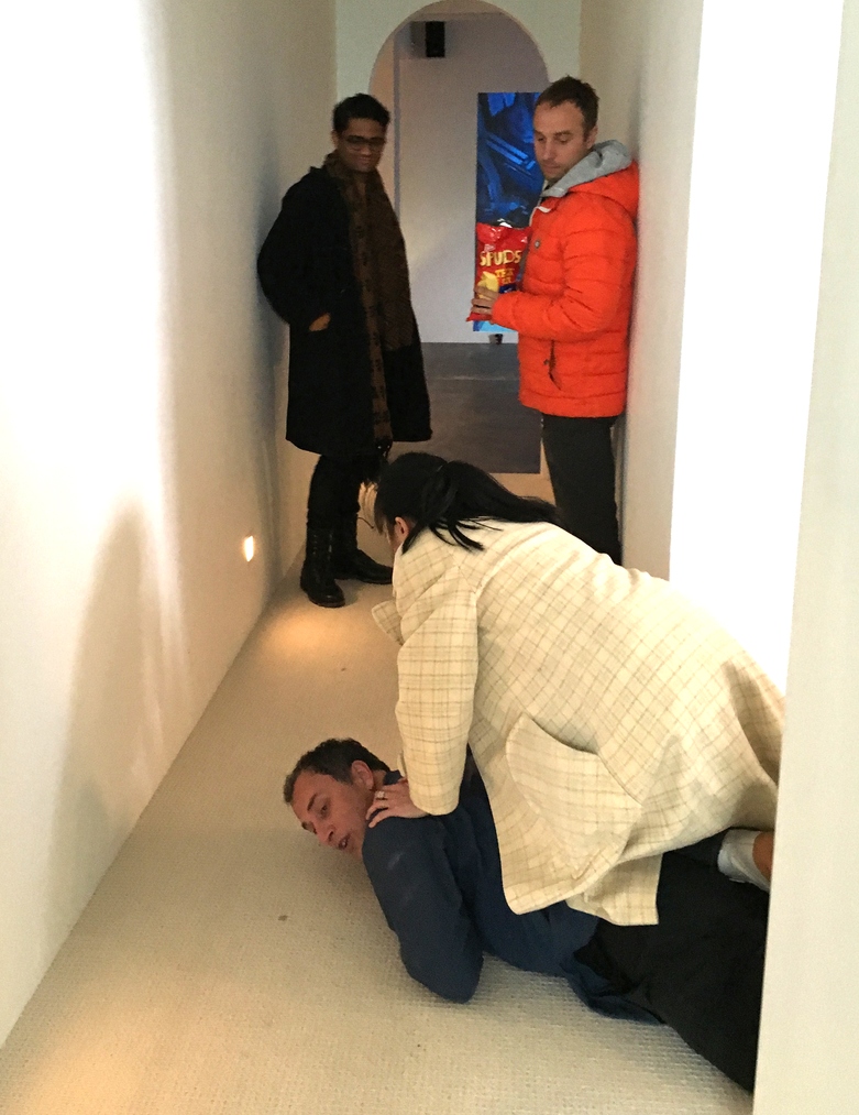 Riff Raff take turns sitting on Mark Harvey’s back during his performance, Feedback, White Hole.